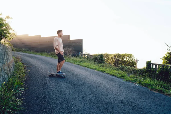 Asfalt yolda durup günbatımında bir şeyler hayal eden düşünceli genç bir erkek. 20 'li yaşlarda, tatillerde boş zamanlarında uzun panolarda dinlenen yetenekli bir beyaz adam.