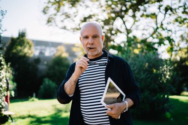 Modern dokunma yastığıyla son sınıf öğrencisinin yarım boy portresi. Boş zamanlarında poz veren Kafkasyalı yaşlı turist. Elinde dijital tabletle seyahat sırasında kameraya bakıyor.