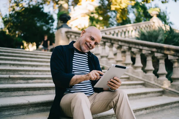 快乐的高加索博客作者在楼梯上休息 使用现代触摸板与4G无线网络连接 穿着休闲装 面带微笑的男士预订 — 图库照片
