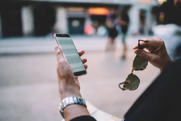オンラインメッセージングのための4G無線接続を持つ男性観光客保持サングラスやスマートフォンガジェットのトリミング画像 携帯電話でのテキストチャット中に認識できない男読書テキスト出版 — ストック写真