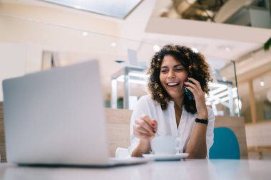 Neşeli grafik tasarımcısı 4G kablosuz internete bağlanıyor. Fikirleri tartışmak için meslektaşlarına telefon açıyor, akıllı telefon konuşmalarını seven gülümseyen bir kadın ve dizüstü bilgisayar ağı kuruyor.