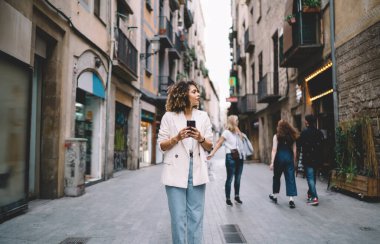 Moda giyinmiş seyahat blogcusu 20 'li yaşlarda. Kaçış turistik tatilleri sırasında yeni şehri keşfediyor. Kafkasyalı hippi kız, modern akıllı telefon teknolojisiyle 4G kablosuz bağlantı kullanıyor.