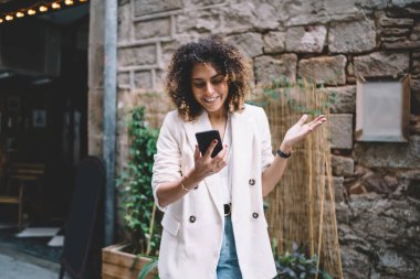 Moda kıyafetleri içindeki mutlu beyaz kadın cep telefonu teknolojisinden gelen kısa mesajları okuyor, neşeli hippi kız mobil sohbetten zevk alıyor online web rezervasyonları yapmak için uygulama kullanıyor.