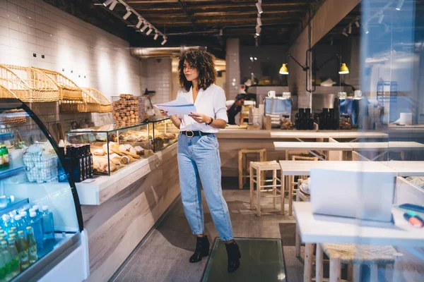 Smart Casual Female Manager Checking Showcase Goods Analyzing Paper Statistics — Stockfoto