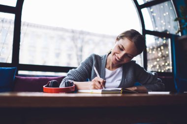 Modern kafe 'de vakit geçirirken kulaklık takmış, deftere kulaklık takmış, mutlu kadın figürleri.