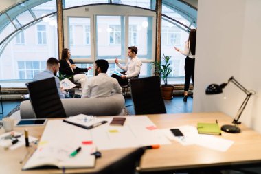 Zarif takım elbiseli zeki meslektaşlar modern ofiste masa başında kırtasiyeli yeni bir iş projesinde çalışıyor.