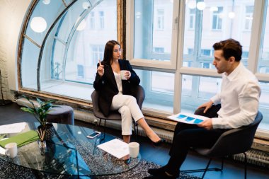 Genç zeki hevesli girişimciler rahat koltuklarda oturup modern aydınlanmış konferans salonundaki iş projesinin stratejisi hakkında konuşuyorlar.