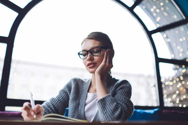 Low Angle Dreamy Female Student Glasses Sitting Table Leaning Hand — Foto Stock