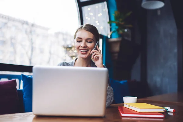 Optimistic Female Remote Worker Browsing Opened Laptop Having Conversation Mobile — Fotografia de Stock