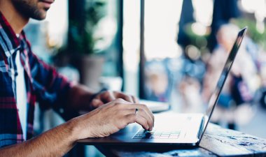İnternet kablosuz internete bağlı modern dizüstü bilgisayarda uzaktan çalışan tanınamayan bilişim programcısının kırpılmış görüntüsü, web içeriği yaratmak için netbook 'a uygulama yükleyen yetenekli bir adam
