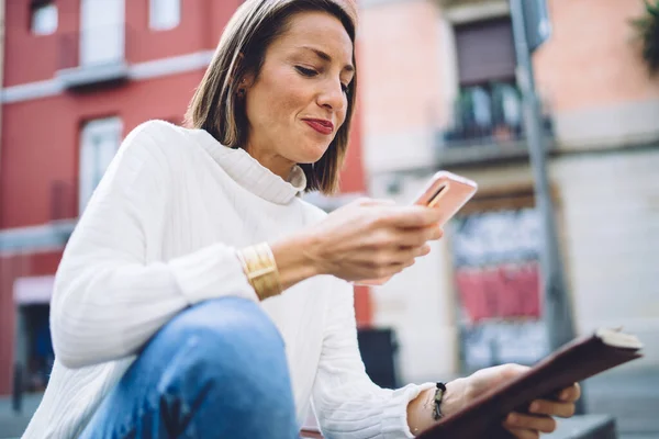앉아서 스마트폰으로 공책을 여성의 — 스톡 사진
