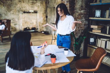 Hüsrana uğramış genç bayanlar üniversite projesinde birlikte çalışıyorlar ve çağdaş iş yerinde masada toplanırken ellerini korku içinde açıyorlar.