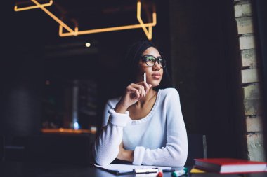 Modern iş yerinde yeni bir proje üzerinde çalışırken gündelik giysiler içinde ciddi siyahi kadın uzaktan işçi bakışları başka yöne bakıyor.