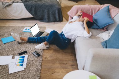 Yüzü defterle kaplanmış, netbook kullanırken yorgun hisseden ve belgelerle uğraşan yüzsüz, uzaktan kumandalı kadın bir vücuttan.