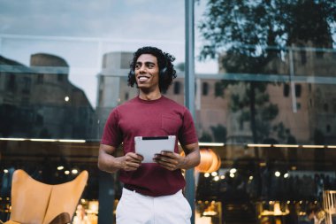 Dokunmatik ped teknolojisi olan mutlu bir milenyum insanı kente gülümseyip popüler müzik şarkılarıyla pozitif müzik listesinin tadını çıkarıyor. Dijital tabletli neşeli hipster adam sesi yüksek sesle dinliyor.