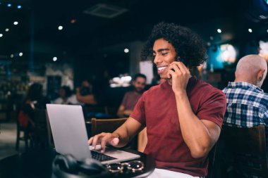 Mutlu erkek, kahvede akıllı telefon konuşmaları sırasında sosyal medyayı tartışırken komik videolar izliyor ve gülümsüyor. Neşeli serbest çalışan internet sitesi dizüstü bilgisayardan arıyor.