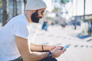 Türk seyahat blogcusu telefon görüşmesi yapıyor, internet takipçileriyle sohbet ediyor, tatillerde geziniyor, cep telefonu teknolojisiyle güneş gözlüklü hippi adam web sitesinde geziniyor.