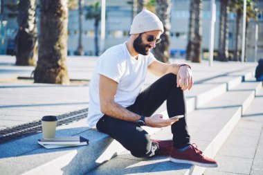 Cep telefonu uygulaması üzerinden internet rezervasyonları yapmak için 4G 'ye bağlanan sakallı erkek blogcu, sosyal ağ kurma sırasında yakışıklı Orta Doğulu kullanıcı mobil uygulaması kuruyor