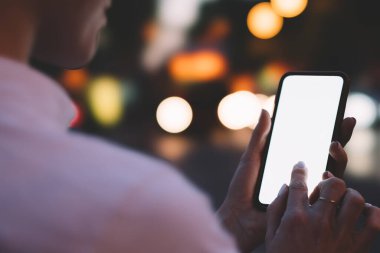 Çağdaş cep telefonunun boş ekranında mesajlaşan isimsiz kişilere mesaj at ve internet üzerinden gece şehrinin bokeh arka planında iletişim kur