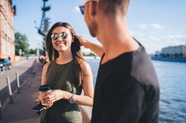Neşeli erkek ve kadın, kahve saatinde canlı iletişim için yapılan olumlu dostça bir toplantı sırasında gülüyor. Moda güneş gözlüklü çeşitli turistler seyahat planını tartışıyor ve gülüyor.