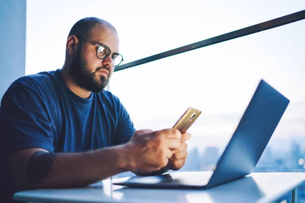 Low Angle Serious Bearded Male Sitting Laptop Using Mobile Phone — Photo