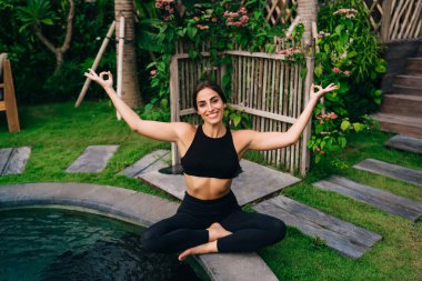 Havuz başında meditasyon sırasında Lotus pozu veren mutlu beyaz kadın portresi, kameraya gülümseyen dişi yogi Zen harmonisi çalışırken kaygısız hissediyordu.