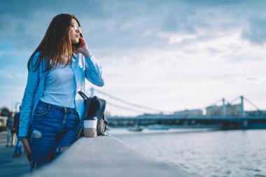 Gözlüklü çekici beyaz kadın cep telefonu internet bağlantısını kullanarak milenyum kadın turistinin sette uluslararası mobil konuşma yapmasını sağlıyor.