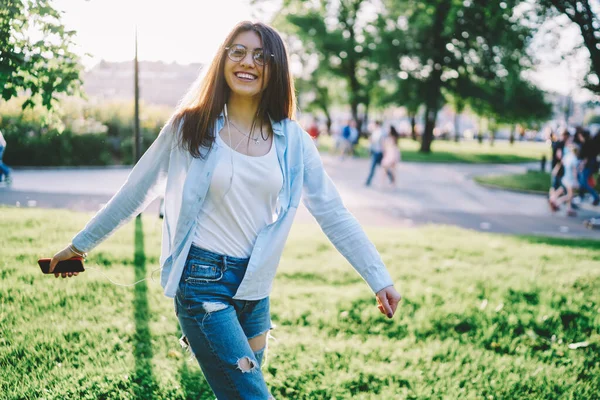 Göz giysisi ve elektronik kulaklıklı neşeli kadın blog yazarının yarım boy portresi, boş zamanların tadını çıkaran mutlu Kafkasyalı blogcu cep telefonu cihazıyla kameraya gülümseyen ve medya kayıtlarını dinleyen