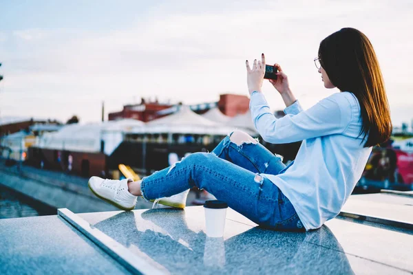 Gündelik giysiler giymiş genç bir kadının modern akıllı telefondan fotoğraf çekerken arka plan görüntüsü. Hücresel uygulamayla video bloğu etkileyen yenilikçi kız 4G kablosuz bağlantı kullanıyor.