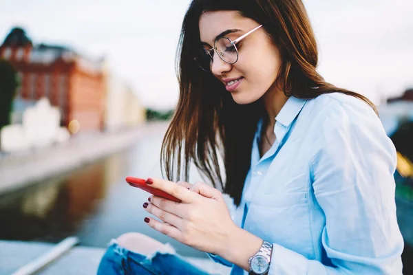 ソーシャルメディアでスマートフォンのメールメッセージを楽しむ光眼鏡のケアフリーヒップスターの女の子 レジャー時間の間にネットワークへの共有のためのアイウェア入力テキストコンテンツで幸せな白人ブロガー — ストック写真
