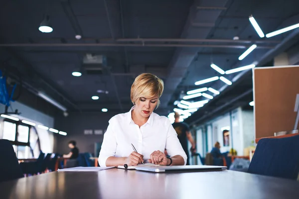 Middle Aged Female Manager Looking Signing Documents While Sitting Table — Foto de Stock