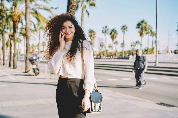 Portrait Cheerful Female Tourist Curly Hair Smiling Camera While Using — Stockfoto