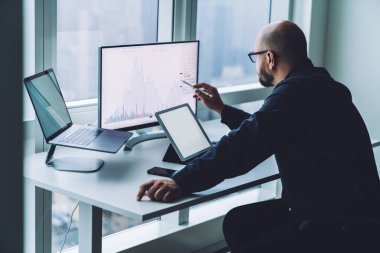 Modern çalışma alanında multimedya cihazları kullanırken masaüstü bilgisayarında Stylus ile grafikleri gösteren tanınamayan erkek ekonomistin yan görünümü