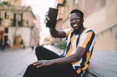 İnternet reklamınız için fotokopi alanı olan modern boş hücresel aygıtlara seçici odaklanma, akıllı telefon teknolojisini elinde tutan bulanık siyah erkek blogcu metin yayını için ekran oluşturur