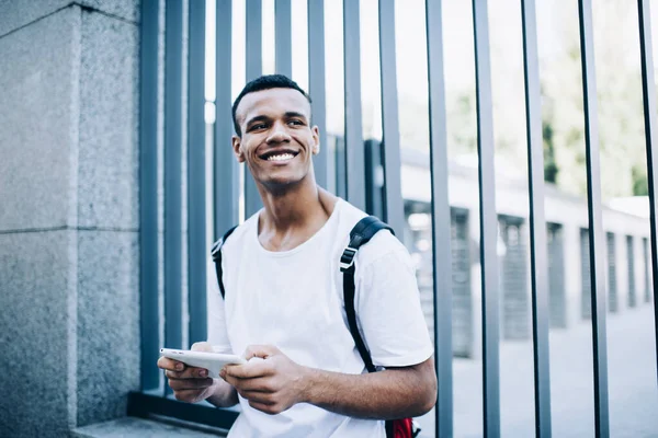 Smiling African American Male Looking Away Browsing Cellphone While Standing — Zdjęcie stockowe