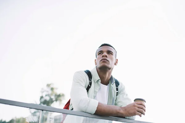 Thoughtful Young Black Guy Casual Clothes Backpack Leaning Glass Fence — стоковое фото