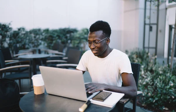 Smiling Black Guy White Shirt Eyeglasses Typing Laptop Sitting Table — Stock fotografie