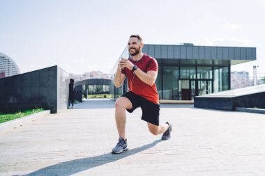 Elinde telefon olan, kulaklıkla müzik dinleyen, gözlerini kaçırıp şehir merkezinde ısınan bir sporcu vücudu.