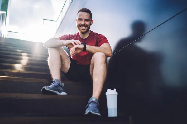 Joyful Male Runner Activewear Sitting Steps Plastic Bottle Looking Camera — Stockfoto