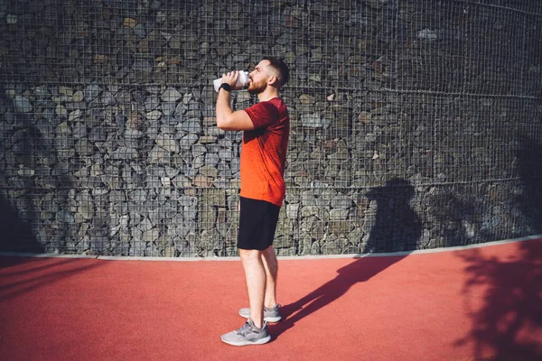 Side View Muscular Sportsman Sportswear Standing Barrier Drinking Plastic Bottle — Stock Photo, Image