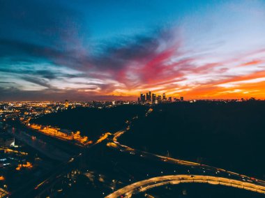 Los Angeles, ABD 'de alacakaranlıkta şehir merkezinde parlayan ışıklar ve trafik kavşağı olan çağdaş şehrin hava görüntüsü