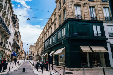 Gündüz vakti Fransa 'da Bordeaux şehir merkezindeki eski binalar arasında modern mağazanın yanındaki kaldırımlı dar bir sokak.