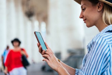 Yaz günü Roma 'yı gezerken, akıllı telefondan notlar alırken tarihi kalenin yanında duran neşeli bayanın yan görüntüsü