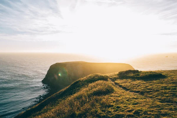 Sakin Okyanusta Uzak Bir Taş Çimenli Tepenin Yakınında Güneş Batarken — Stok fotoğraf
