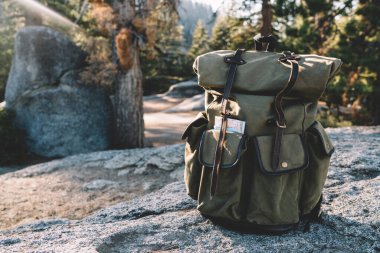 Güneşli bir günde Amerika 'daki Yosemite Ulusal Parkı' nda taşlı bir zemine yerleştirilmiş yalnız ve şık bir turist sırt çantası.