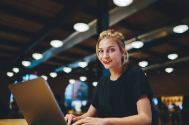 Kameraya gülümseyen mutlu Kafkasyalı metin yazarı portresi, birlikte çalışma alanında mesafelere giderken gülümseyen, bilgisayarlı neşeli kadın blogcu masa başında poz verdiği için masa başı bilgisayarında poz veren