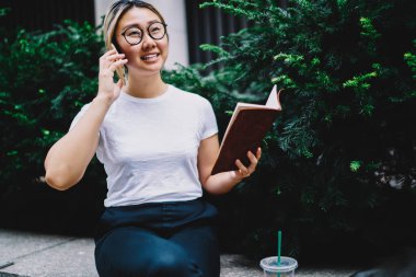 Optik gözlüklü çekici bir kadın seyahat planlarını tartışmak için gezinti bağlantısını kullanıyor, güzel bir Japon kız öğrenci ve cep telefonu uygulaması ile telefon ediyor.