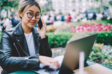Modern dizüstü bilgisayarda uzak mesafe işi yapmak için çekici Japon bilişim uzmanlarının portresi, arama ve konuşma için 4 G 'ye bağlanan gözlüklü yetenekli kadın.