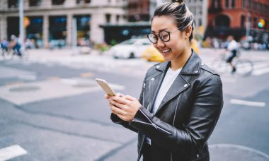 Gezici teknolojisi olan neşeli bir binyıl blogcusu solo tatillerde kameraya gülümsüyor, elinde akıllı telefon cihazı olan komik Japon kız şehir seyahatinin tadını çıkarıyor.