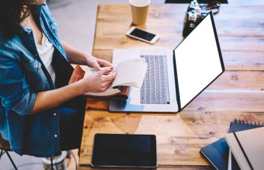 Bilgi sitesinde reklam metni için boş ekran alanı olan dizüstü bilgisayarda öğrenim görmek için zaman harcayan yetenekli bayan öğrenci, ders kitabı ile tanınmayan kadın Netbook üzerinde uzaktan çalışıyor.